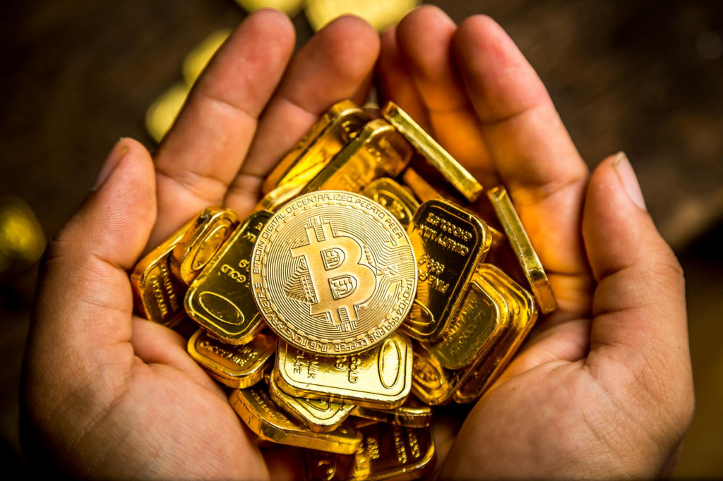 Hands holding Cryptocurrency coin, Bitcoin coin and gold bars. Wooden floor background from top view.