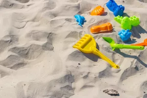 travel background with colorful plastic toys in the sand of a beautiful beach. Kid'S Beach Toys