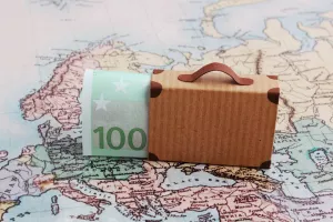 Europe city trip travel budget concept with 100 euro note and suitcase on map