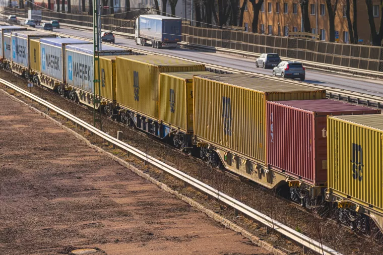 Gothenburg, Sweden - March 01 2026Freight container train transporting cargo alongside urban highway at sunset