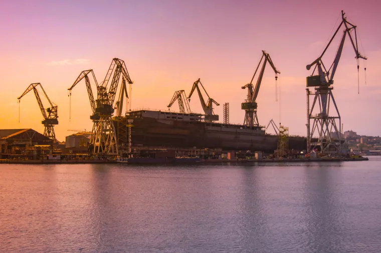 shipyard with large ship under construction at the sunset