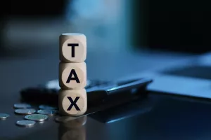 Tax Concept. Wooden Blocks with Calculator and Coins with the Word Tax. Personal Income Tax, Corporate Tax, Financial Research, Documents, Reports and Calculations Concept.